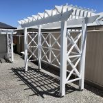 This painted white Pergola has X screening across the back and sides that compliment the design accents of the house.